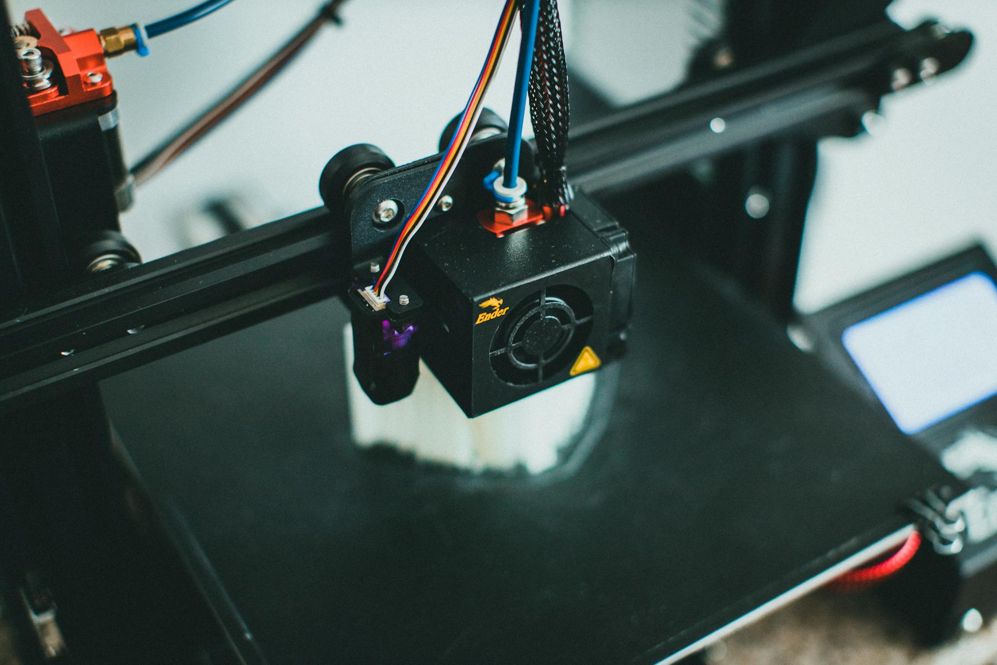 Detailed shot of a 3D printer creating an object, focusing on the cooling fan and print head.